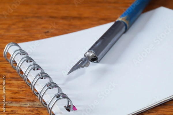 Fototapeta A fountain pen with a pen and a notebook on a wooden table