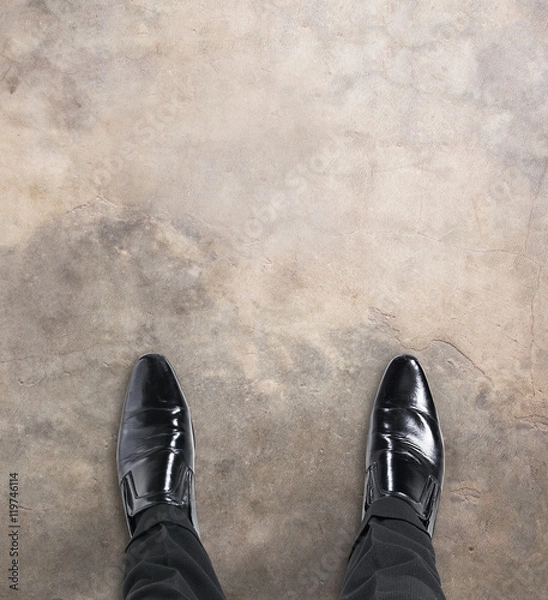 Fototapeta Business man standing at the beginning of a journey looking down at his feet