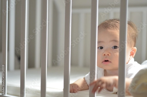 Fototapeta ベッドの柵ごしの赤ちゃん