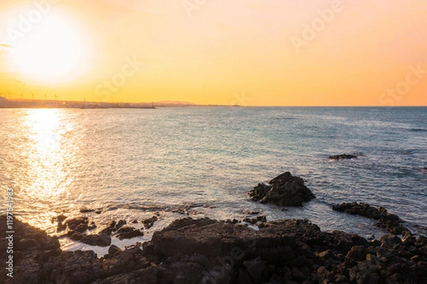 Obraz Sunset sky over a rocky beach