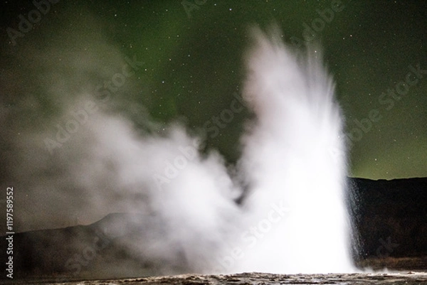Fototapeta Nighttime view of Strokkur geysir erupting under the northern lights in south Iceland