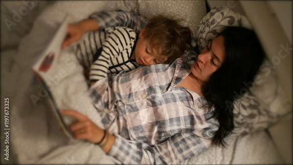 Fototapeta Mom reading bed-time story to toddler son at night before sleep