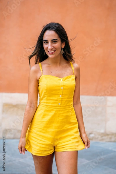 Obraz Young woman smiling and walking in a yellow jumpsuit