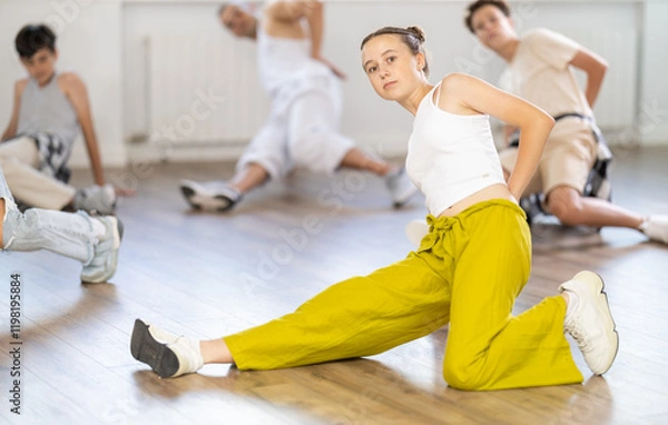 Fototapeta Group of young friends learn group dances - low break and breakdance in dance studio
