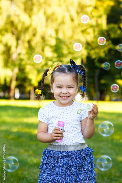 Obraz little girl blowing bubbles in the park