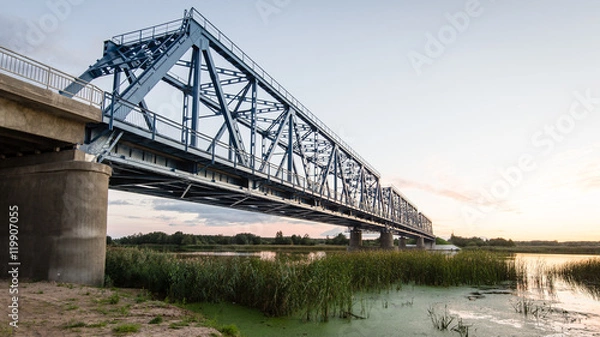 Fototapeta railway bridge with metal rails near river
