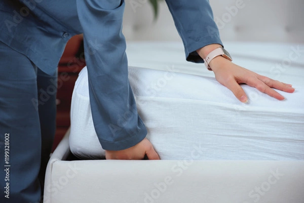 Fototapeta Woman's hand puts a cover on the mattress to protect it from water and house dust mites