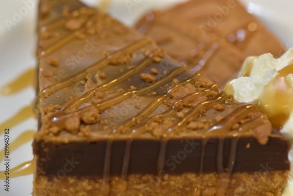 Fototapeta Biscoff Biscuit Cake, a delectable fusion of flavors and textures that is sure to captivate the senses. This three-tiered masterpiece features layers of moist, rich cake.