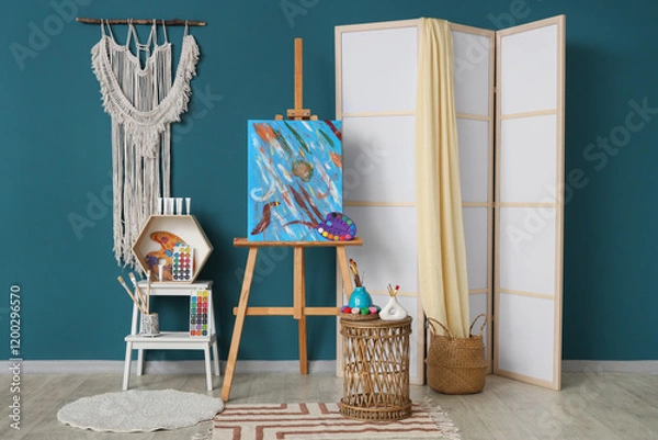 Obraz Interior of artist's workshop with painting on easel, folding screen and art supplies