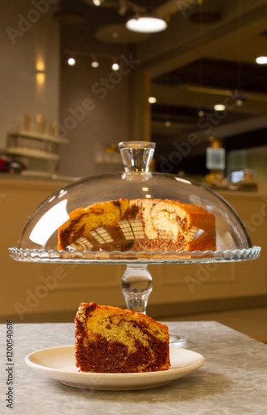 Fototapeta marble cake in cake holder and portion of cake on plate in the coffee shop