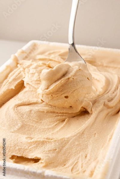 Fototapeta serving vanilla ice cream with a spoon in white bowl, white background