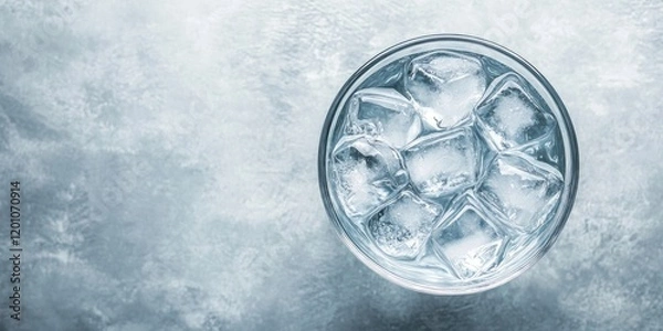 Obraz Glass of water with ice cubes centered on a textured gray background top view ample negative space for text above and below the glass