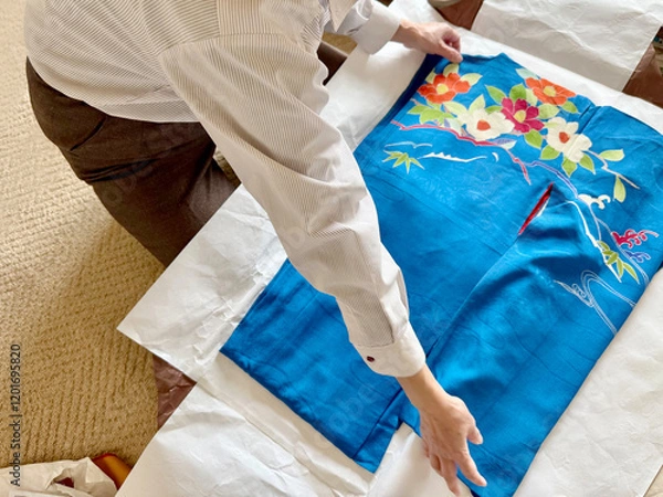 Fototapeta 青色の中振り袖をたとう紙の上で広げる女性の手元