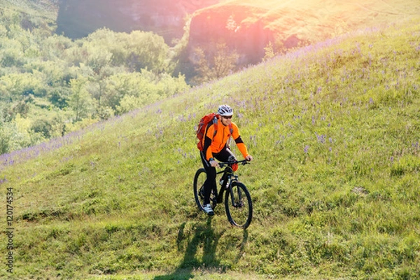 Fototapeta Young man traveler riding on bicycle with red backpack