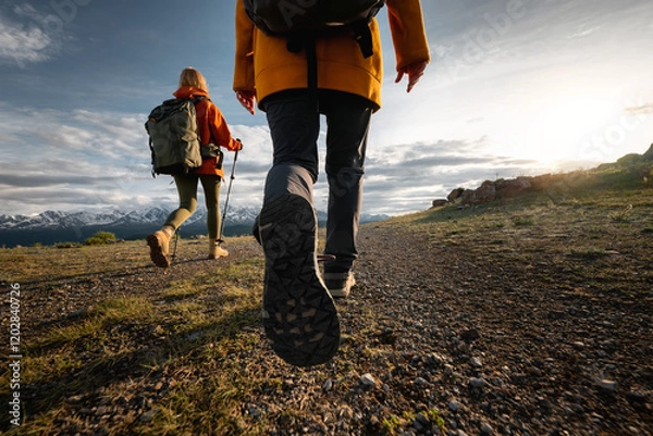 Obraz Two young active female hikers tourists girls walks in sunset mountains. Close up photo of woman legs and boots walking in mountains area