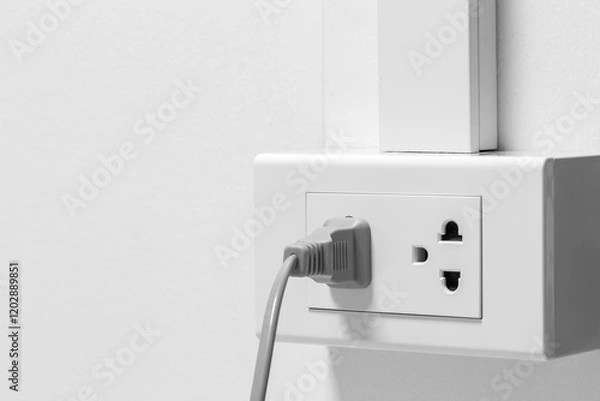 Obraz Plug from an electrical appliance. plugged into an electrical outlet on white wall background.