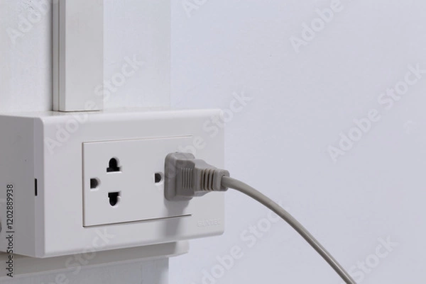 Obraz Plug from an electrical appliance. plugged into an electrical outlet on white wall background.