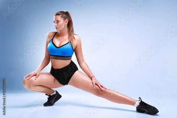 Fototapeta Plus size female model is posing in a fitness style in a studio