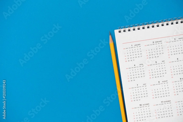 Fototapeta close up of calendar and pencil on the blue table background, planning for business meeting or travel planning concept