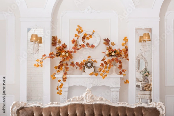 Obraz Żółte liście oplatają ścianę białego holu z ozdobnym klasycznym kominkiem i lustrami