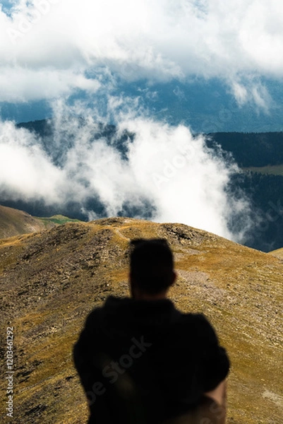 Obraz Persona anónima sentada mirando montañas con nubes