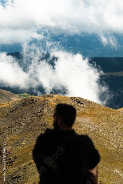 Obraz Persona anónima sentada mirando montañas con nubes