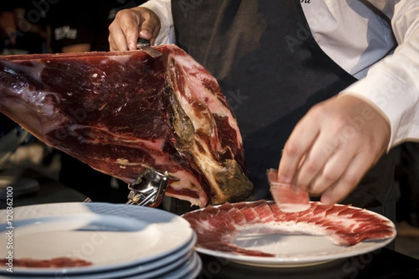 Fototapeta Cortador de jamón cortando un cinco jotas. degustación de jamón ibérico de bellota. Noches gastronómicas de verano.