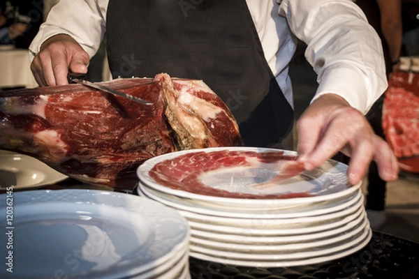 Fototapeta Cortador de jamón cortando un cinco jotas. degustación de jamón ibérico de bellota. Noches gastronómicas de verano.