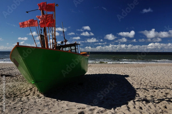 Obraz Zielony kuter rybacki stojący na piaszczystej plaży.