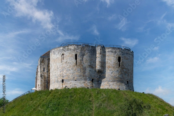 Obraz Low angle view of York Castle a ruined keep or fortification of medieval Norman castle or Clifford's Tower in the city of York, England against a white clouded blue sky