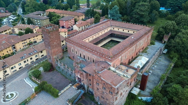 Fototapeta aerial view about Carimate Castle surrounded by green wild forest in sunrise lights