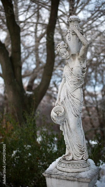 Obraz sculpture of a girl in the winter park. An old statue in a park of a sensual semi-nude Greek or Italian Renaissance woman with a vase. sunny day, spring garden. 