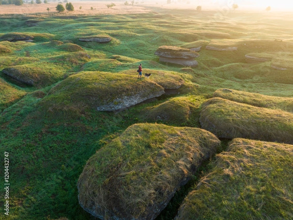 Fototapeta A person with a husky dog on a karst landscape background (drone view).