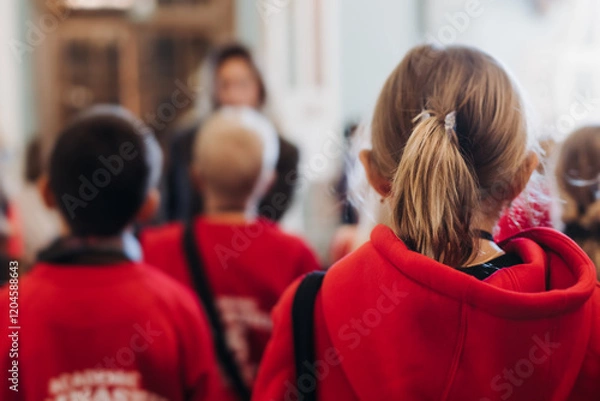 Fototapeta Group of kids children on excursion in a museum gallery, school pupils and students tour with guide, a docent with a tourists, young visitors wearing red, school field trip, art exhibition attendees