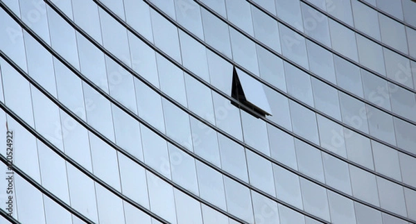 Fototapeta An open window in a row of similar dark office windows depicting a uniqueness concept