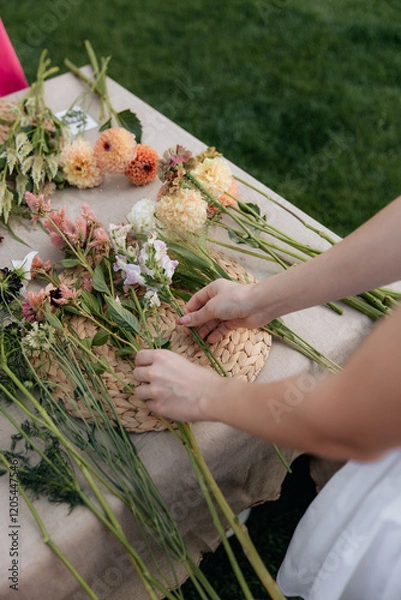 Fototapeta Close-up photo of a florist creating a bouquet of fresh flowers