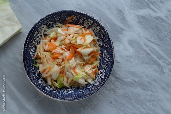 Fototapeta Salad with cabbage and carrots on a plate on a gray table. Top view