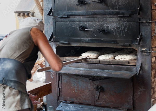 Obraz artisan baker introducing the product in wood oven
