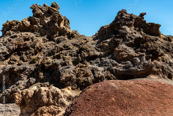 Fototapeta Spektakularne formacje skalne ukazujące surowość i piękno geologicznych procesów, formujące unikalny krajobraz na wulkanicznych pustkowiach pod błękitnym niebem