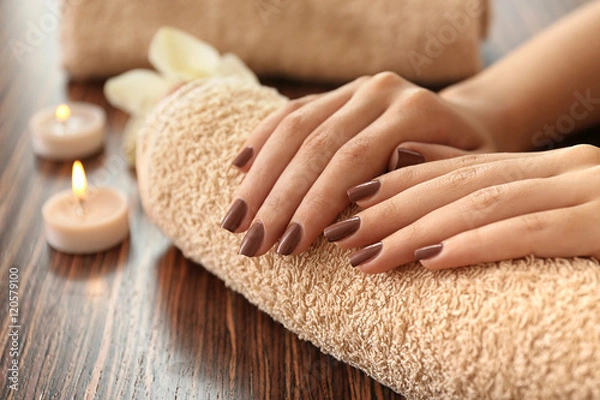 Fototapeta Kobiece dłonie z brązowym manicure na ręczniku