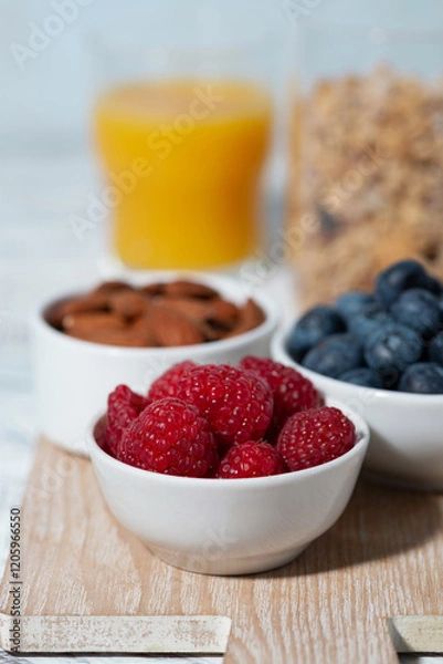 Fototapeta fresh berries, nuts, muesli and orange juice, vertical