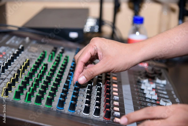 Fototapeta Hands adjusting the knobs and faders on a professional audio mixing console in a studio