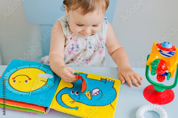 Fototapeta small child playing with soft book