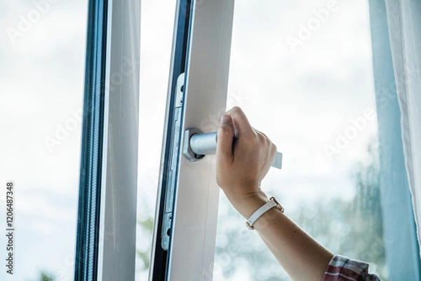 Fototapeta A professional close-up of a woman right hand turning the handle to tilt a luxury PVC window, highlighting superior craftsmanship, durability, and modern functionality.