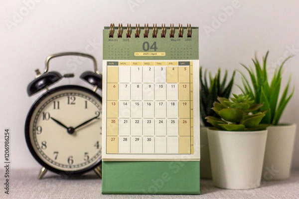 Fototapeta April 2025 calendar and alarm clock on your desktop.