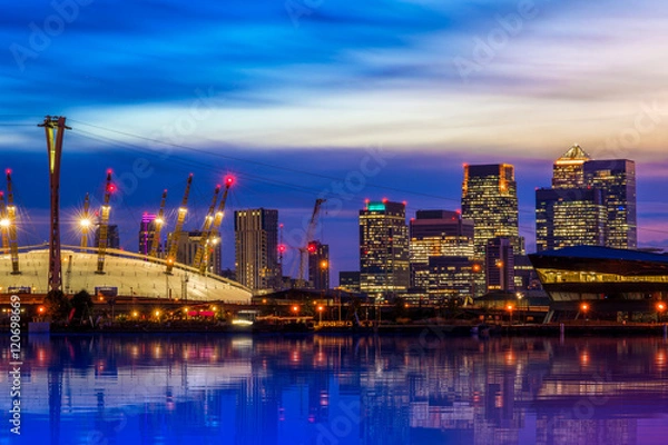 Fototapeta O2 i Canary Wharf z Royal Victoria Dock w nocy w Londynie