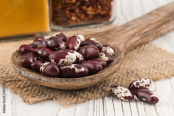Fototapeta Red beans in a wooden spoon on old wooden table.