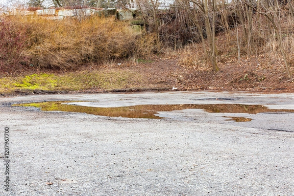 Fototapeta Empty Parking Lot with Puddles and Autumn Landscape Beyond