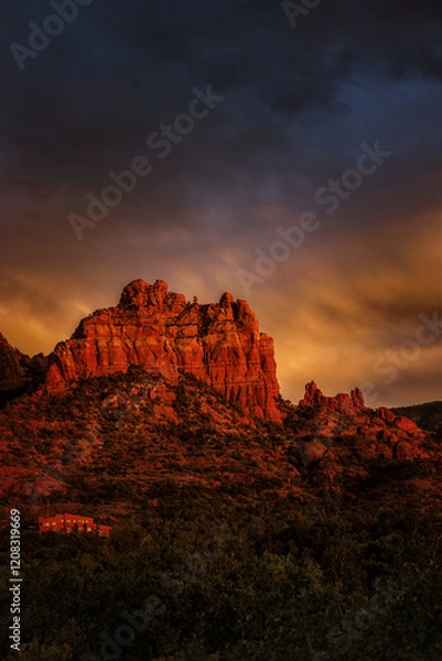 Fototapeta A fiery and dramatic sky during a sunset in Sedona, with the red rock mountains illuminated.