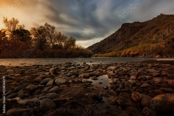 Fototapeta A beautiful sunset along the Salt River, with a fisherman doing some fly fishing, and a great reflection of the mountains.